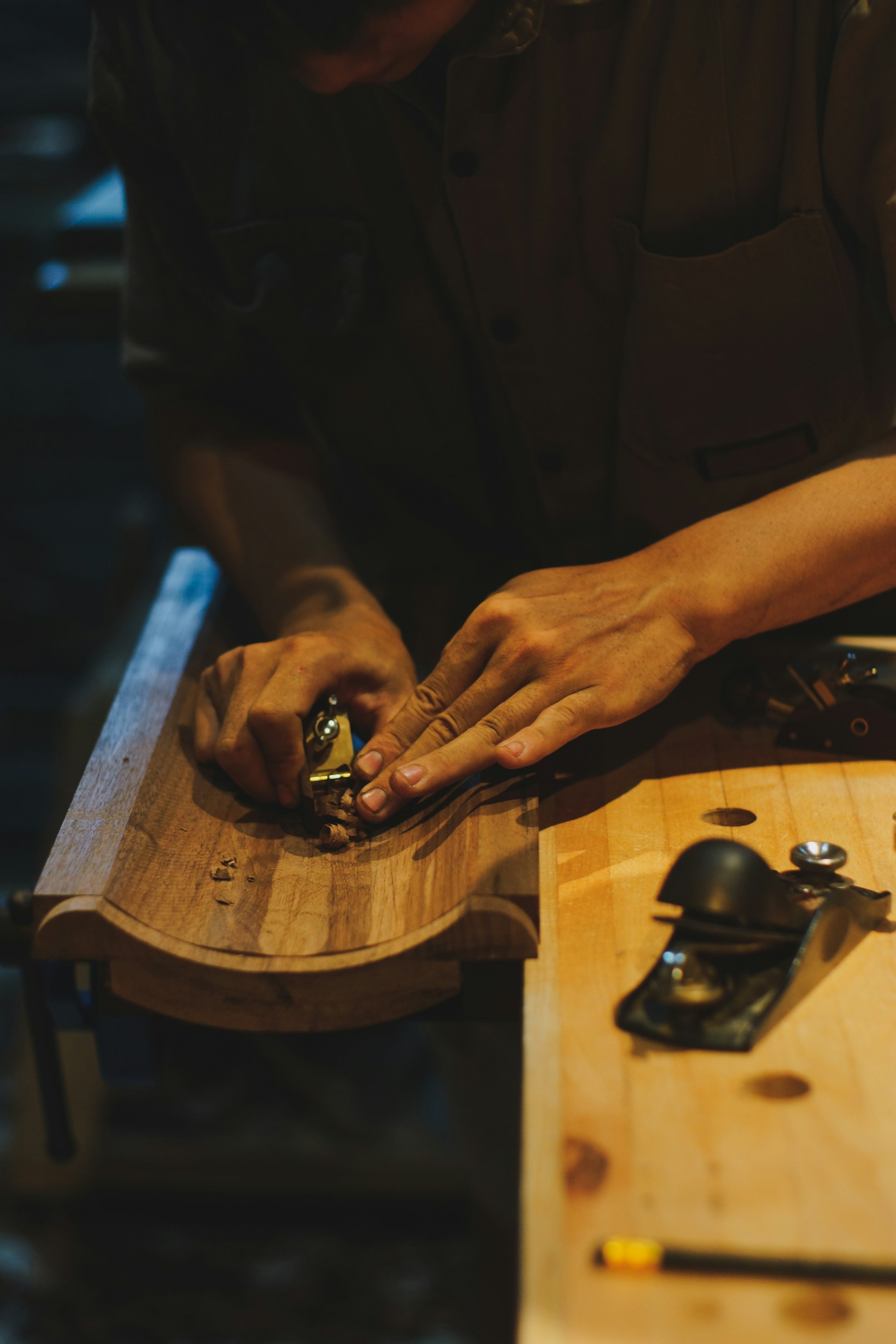 Hands guiding a hand plane along a length of timber