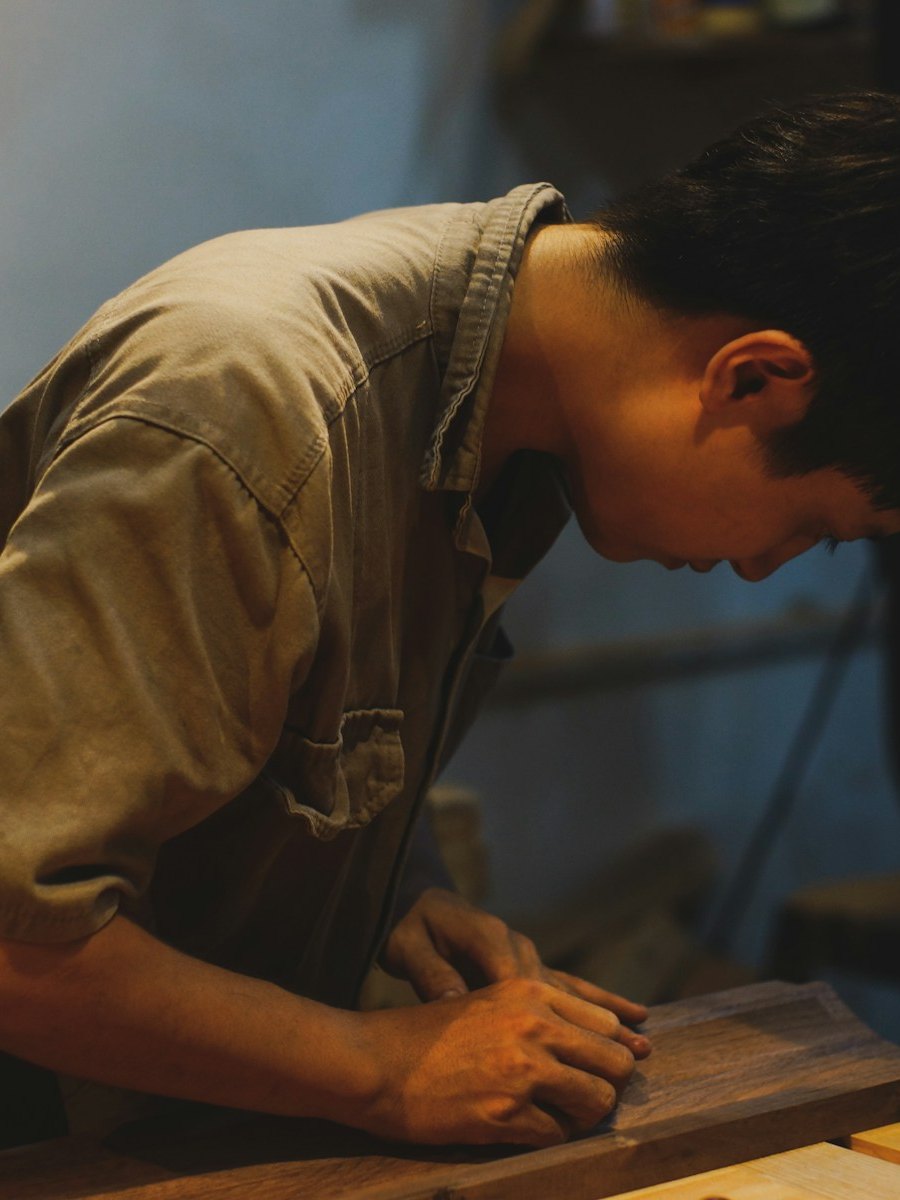 A maker sanding a wooden panel