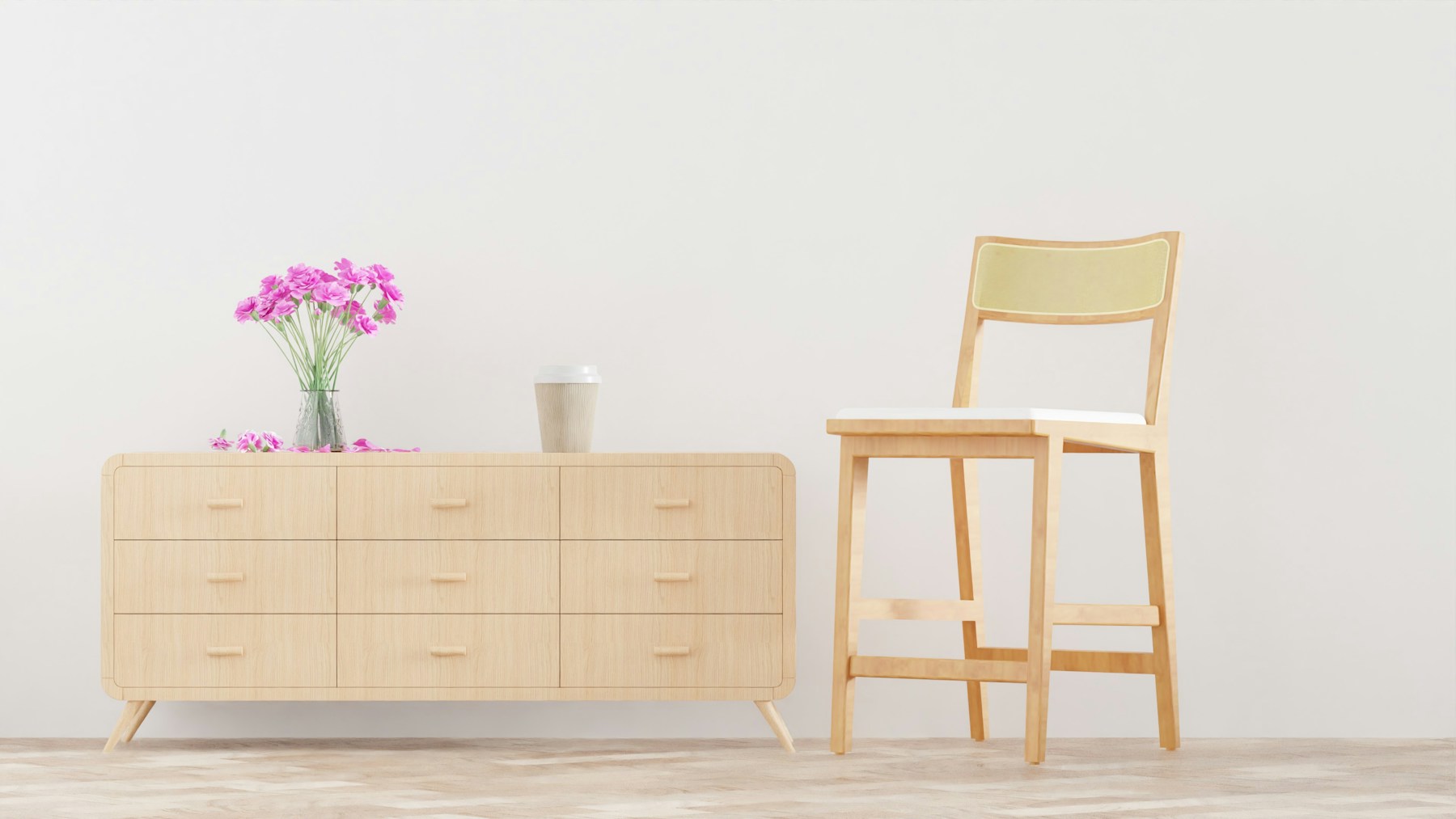 A pale wooden sideboard with a chair and flowers